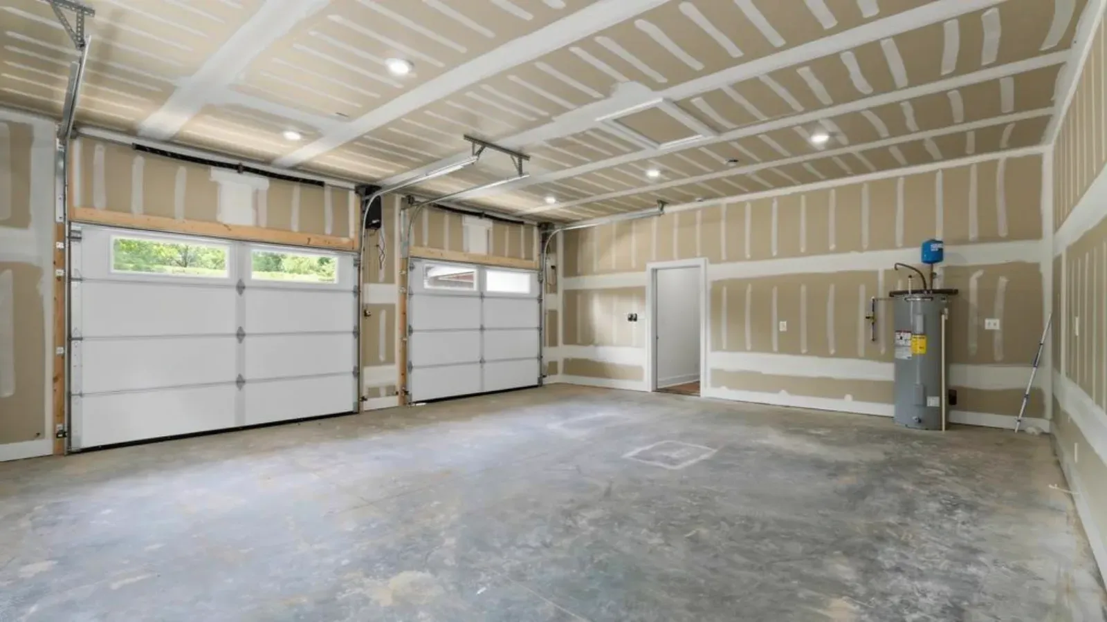 Two-bay garage drywalled and fire-taped across the walls and ceiling, with a water heater against the side wall