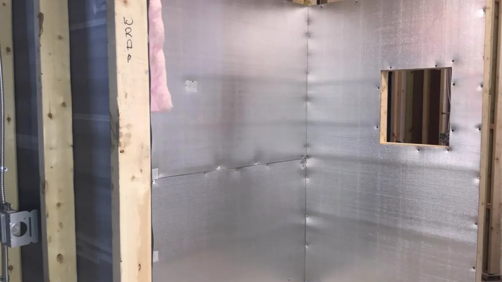 Lead radiation shielding sheet lining a framed wall, panel seams lapped and fastened, ready for the finish drywall layer